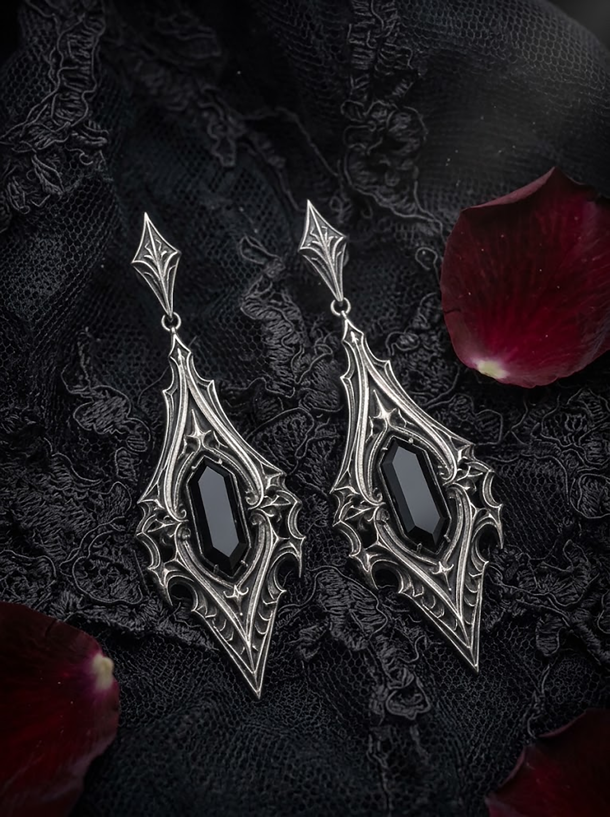 kurgaatelier gothic drop earrings with black gemstones laid on dark satin with red rose petals for romantic alternative wedding jewelry