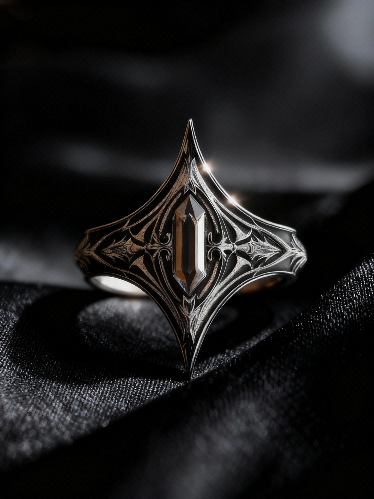 Close-up of Kurga Atelier pointed gothic black stone ring on black silk fabric. Oxidized silver statement ring with medieval cathedral engraving.