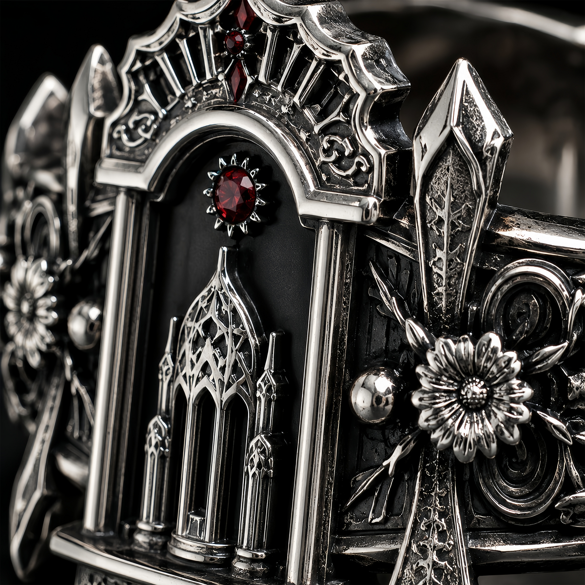 Detailed macro view of silver reliquary ring showcasing hand-carved floral motifs, oxidized vintage finish, and red gem.