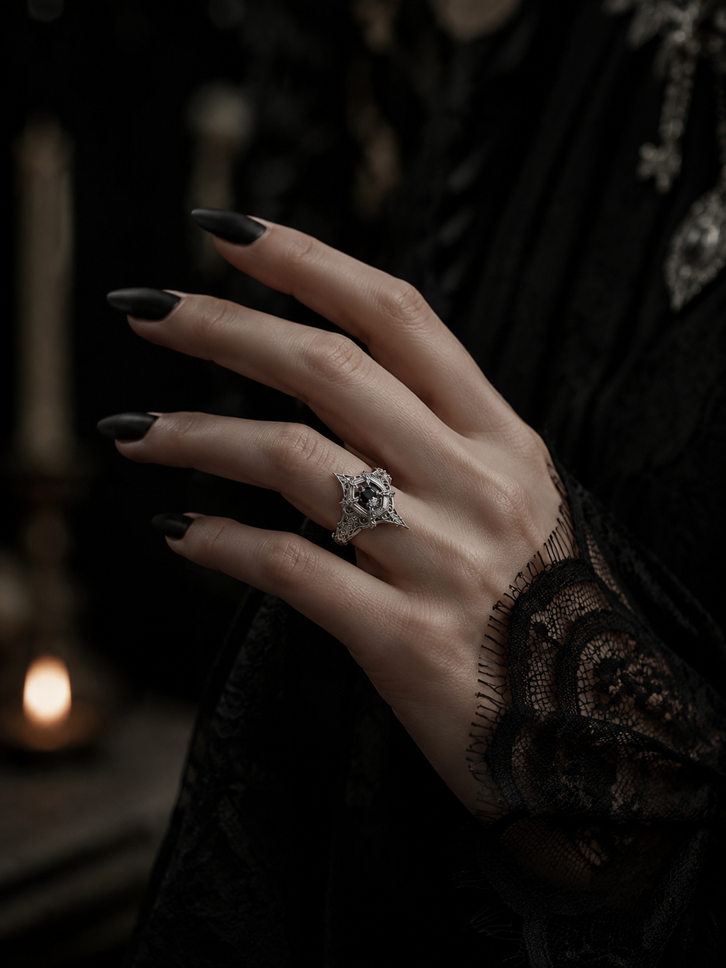 Model wearing the gothic engagement ring by Kurga Atelier. Vintage dark academia aesthetic black gemstone cathedral ring styled with a lace cuff and black nails.