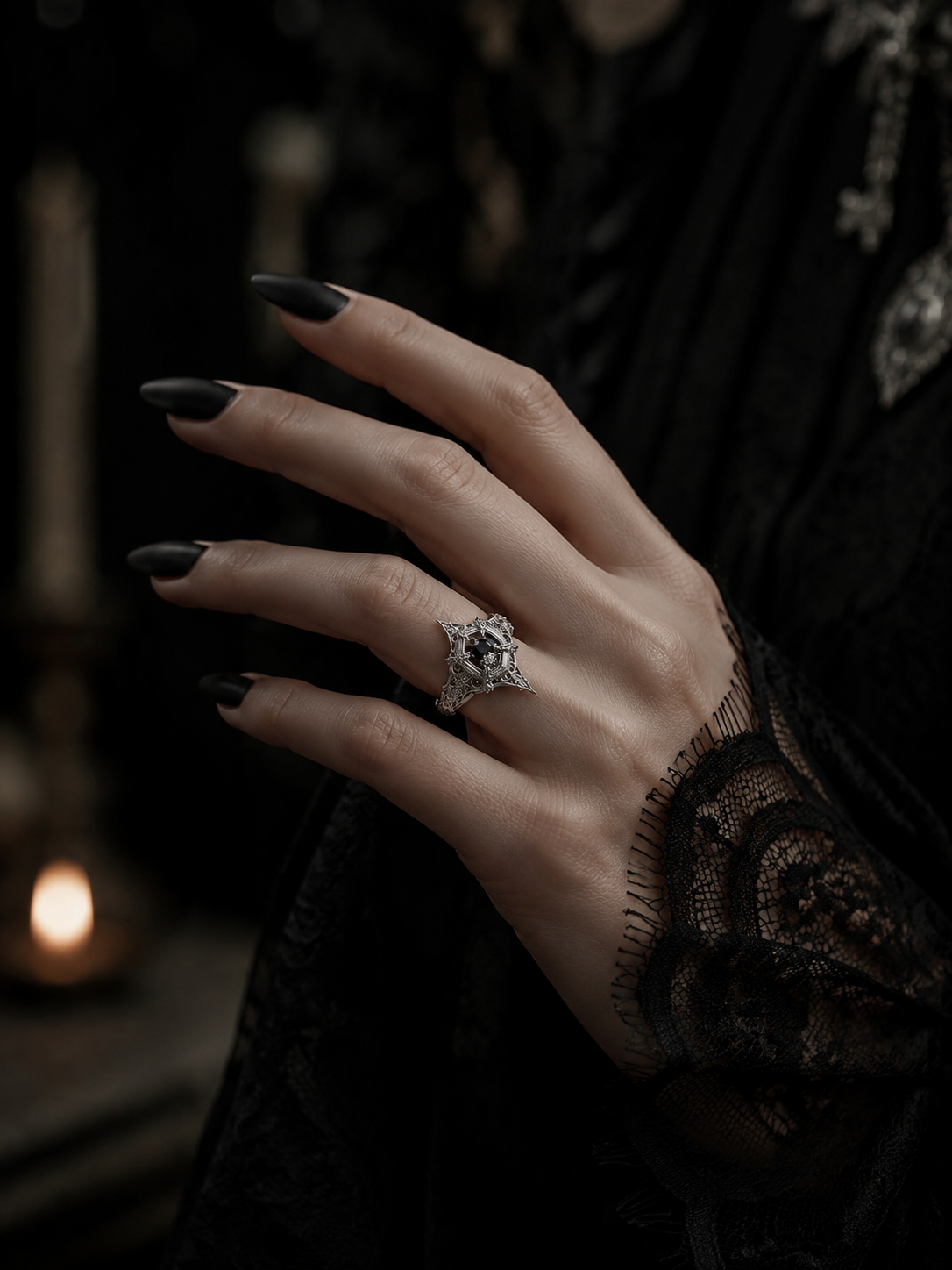Model wearing the gothic engagement ring by Kurga Atelier. Vintage dark academia aesthetic black gemstone cathedral ring styled with a lace cuff and black nails.