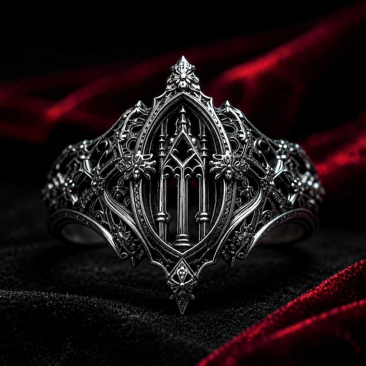 Kurga Atelier handcrafted solid silver gothic cathedral ring set against rich dark red velvet fabric, highlighting vampire goth filigree architecture and honeybee accents.