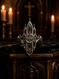 Gothic cathedral architecture ring by Kurga Atelier displayed on a dark velvet altar with burning candles. Features sterling silver spires, window tracery, and a cross emblem for a dark academia witchy goth aesthetic.